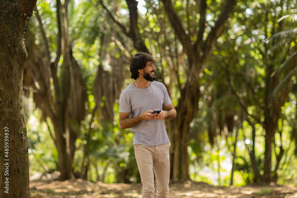 View of young man using a smartphone at day time with a green park in the background. High quality photo View of young man using a smartphone at day time with a green park in the background. High quality photo