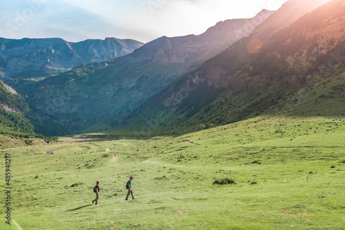 Young Couple hiking in a beautiful valley between mountains during the sunset. Discovery Travel Destination Concept.