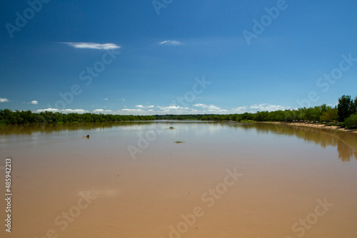Panorama view of the brown water Parana river under a clear blue sky. View of the wide river and jungle reflection in the water.