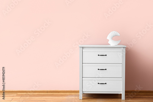 Stylish decor on modern chest of drawers near color wall © Pixel-Shot