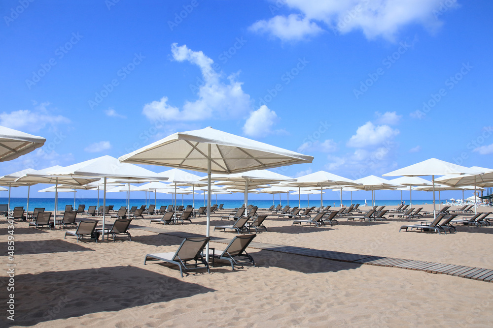 Beautiful tropical  scenery. Loungers, umbrella. Sea. Resort hotel. Rows of folded beach umbrellas and empty sunbeds on the beach. Sea ​​in Turkey. Beach without no tourists because of Covid-19 corona