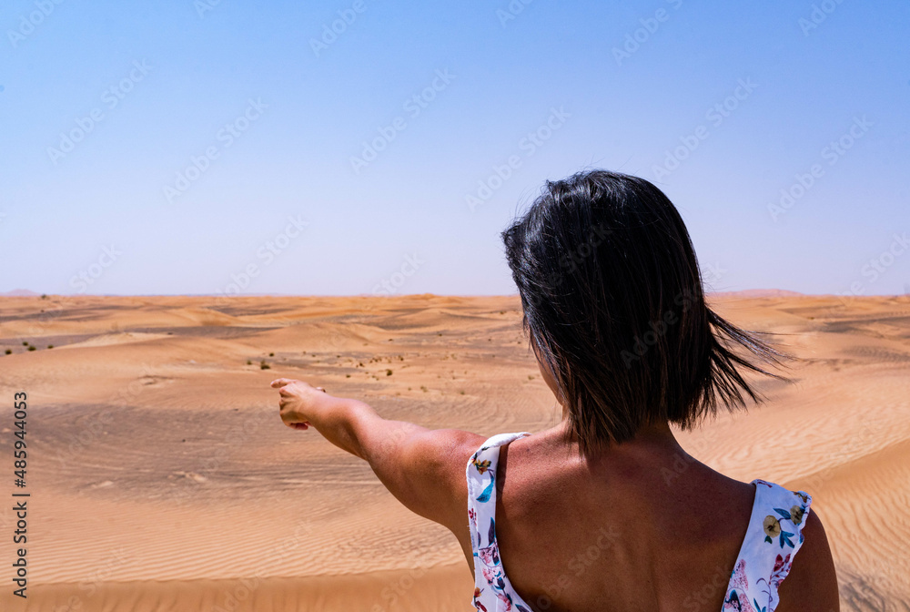 Woman in the desert, pointing to the horizon