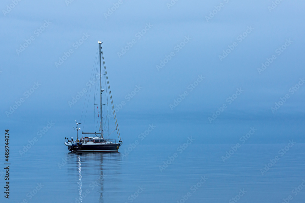 Sailing boat alone in the ocean durig blue hour