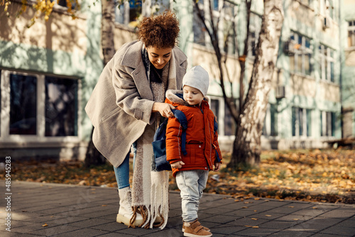 Canvas Print Babysitter in schoolyard and preparing boy for the first day.