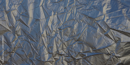 Full frame close-up view of a large wrinkled silver gray metallic tarp