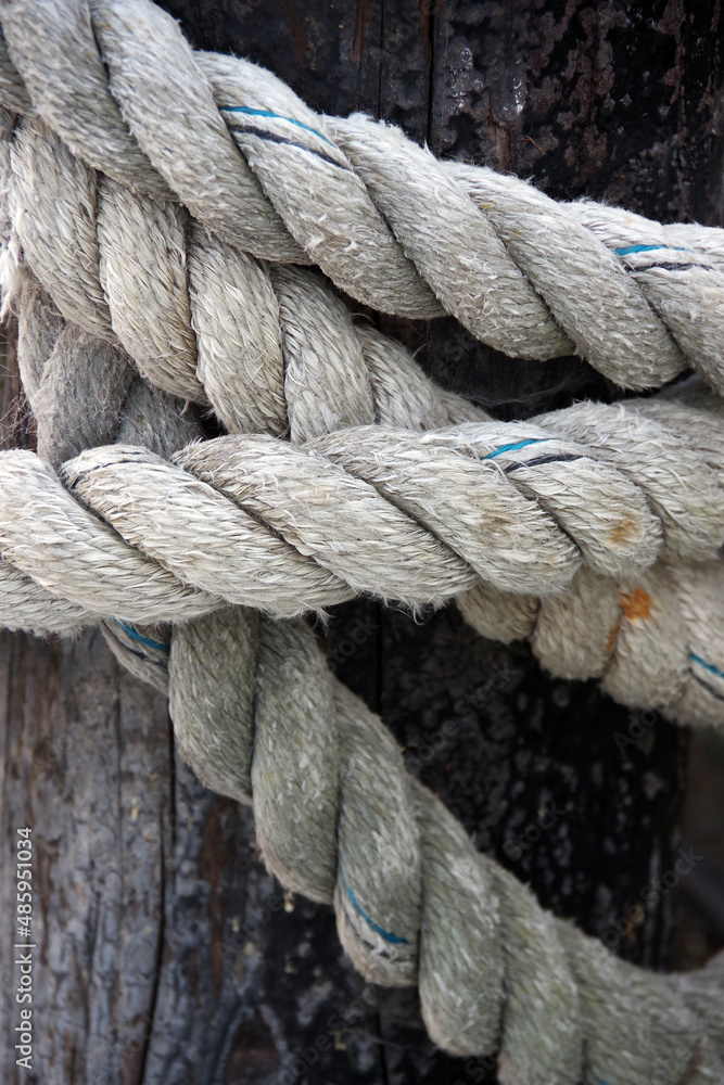 Close-up view of a heavy and strong rope tied around a wooden post