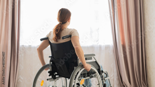 Caucasian woman in a wheelchair at the window. 