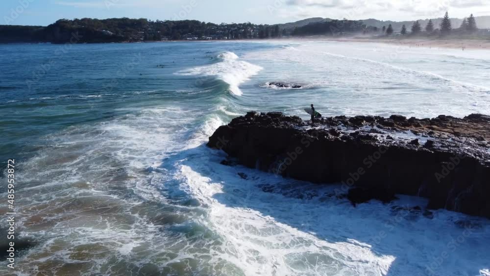 Aerial drone landscape shot of surfer waiting on rocks cliff to go jump and surfing with waves whitewash North Avoca Central Coast NSW Australia 4K Aerial drone landscape shot of surfer waiting on rocks cliff to go jump and surfing with waves whitewash North Avoca Central Coast NSW Australia 4K