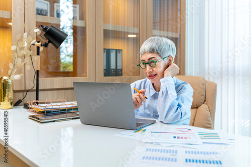 Senior Asian woman business manager analyzing the sales report from marketing team for business income and financial management concept