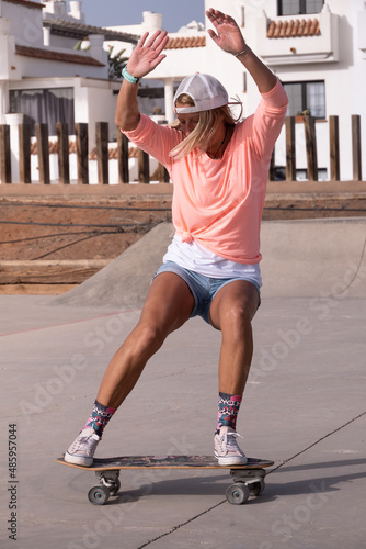 Caucasian woman doing sliding trick in the skate park photo