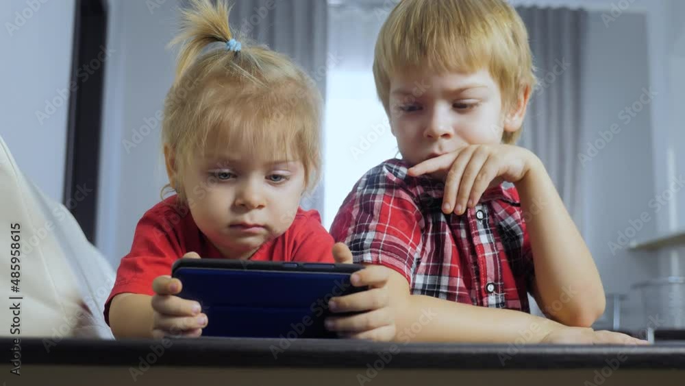 children watch online video cartoons on a smartphone. kids little lifestyle boy and girl brother sister watch online streaming broadcasting the phone children watch online video cartoons on a smartphone. kids little lifestyle boy and girl brother sister watch online streaming broadcasting the phone