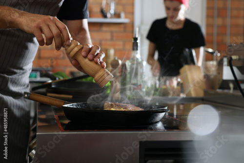 Professional chef cooking meat on stove in restaurant kitchen  closeup