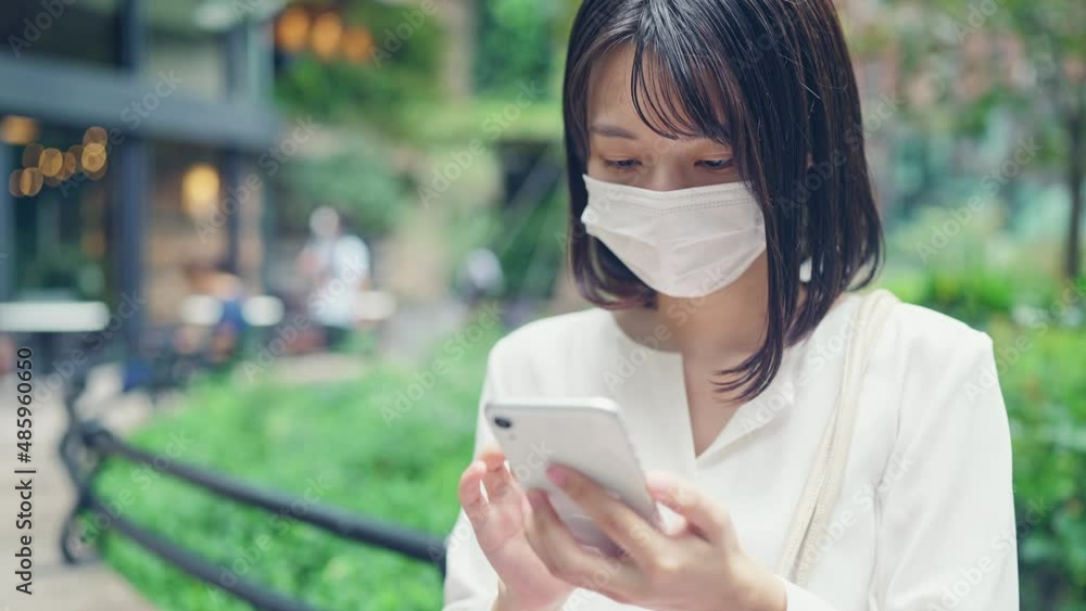 スマホを使うマスクをした女性 スマホを使うマスクをした女性