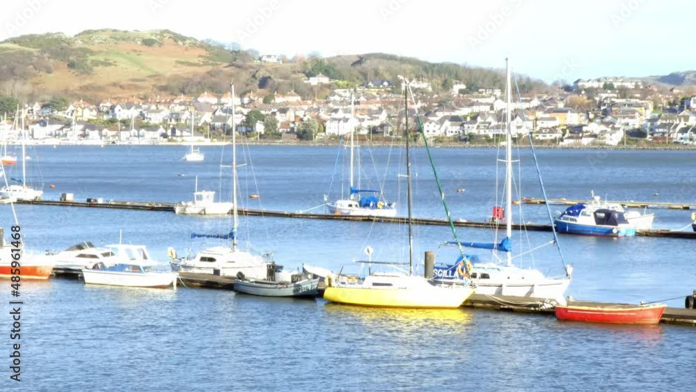 Sunlit yachts and fishing boats moored on harbour pier North Wales coastline scenic mountain town Sunlit yachts and fishing boats moored on harbour pier North Wales coastline scenic mountain town