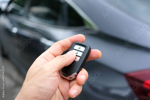 The man in the hand held the remote control of the car, he opened the remote control of the car door. To drive a car
