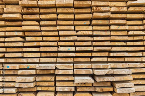 Stacked lumber filling background  wood texture. Stack of new wooden rods in the lumber warehouse.