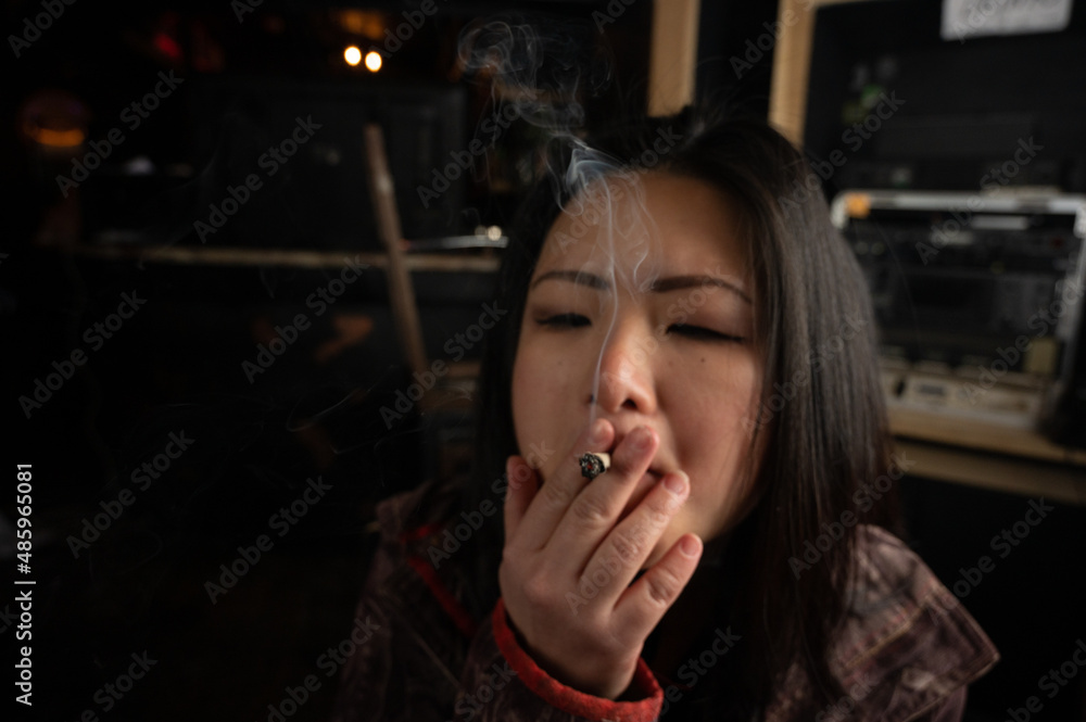 Fotka „Asian girl smoking a weed joint getting high inhaling and