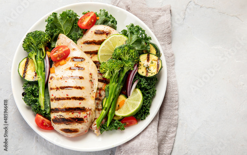 Grilled chicken with vegetables on light background.