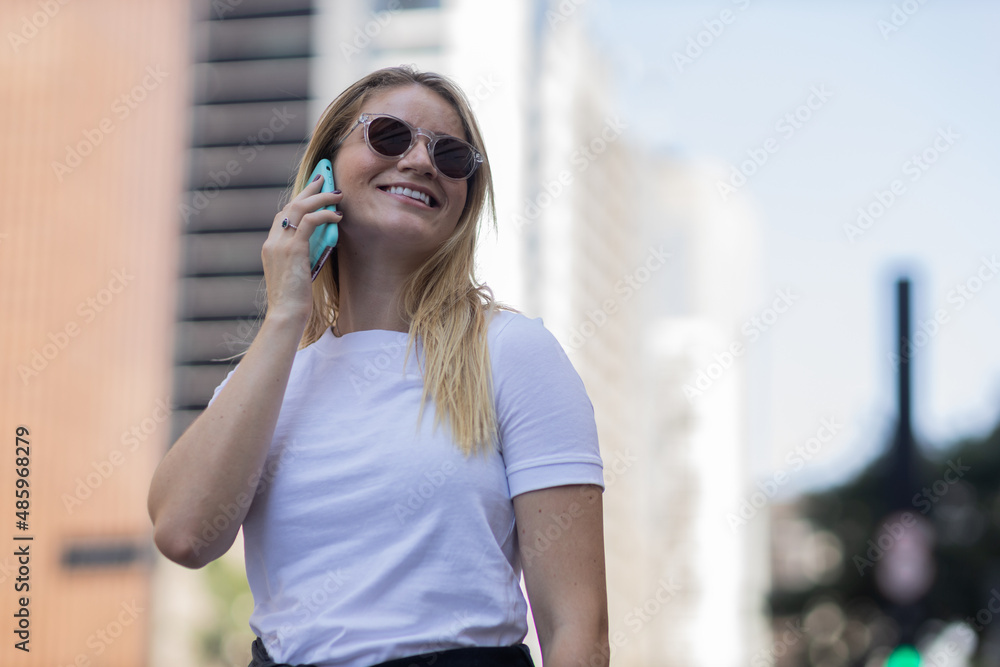 Fototapeta premium Young woman using a smartphone at day time with city view landscape in the background. High quality photo