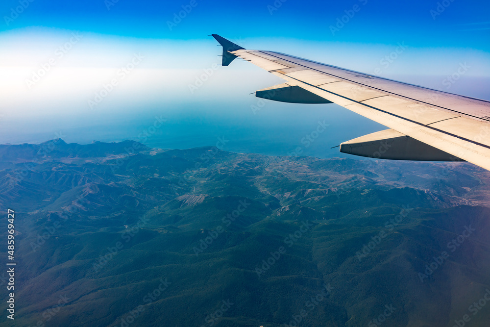 View from the airplane window at a beautiful blue clear sky and the airplane wing View from the airplane window at a beautiful blue clear sky and the airplane wing