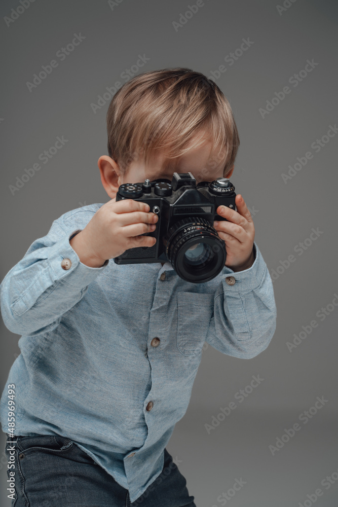 Cheerful child photographer with camera against gray background Cheerful child photographer with camera against gray background