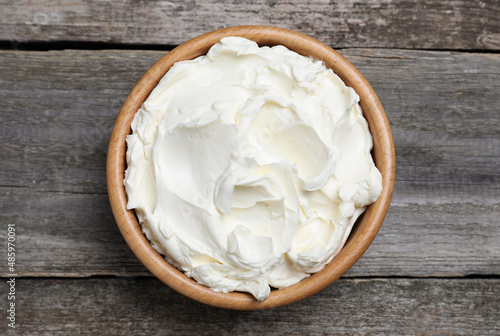 Bowl of tasty cream cheese on wooden table, top view