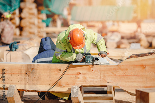 Foto Industrial work carpenter grinds log with electric jointer, construction frame b