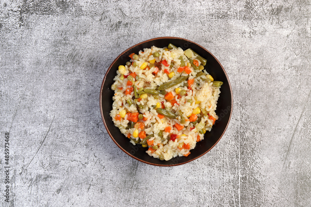 Colorful Rice with green beans, carrots, onions and bell peppers in a bowl on a dark background. Top view, flat lay. Colorful Rice with green beans, carrots, onions and bell peppers in a bowl on a dark background. Top view, flat lay.