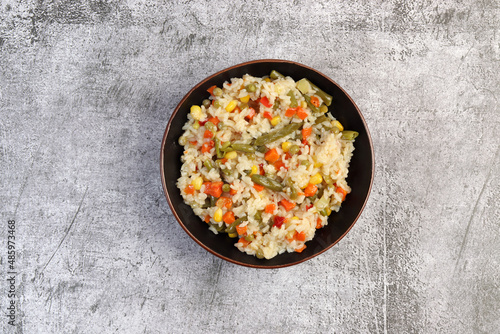 Colorful Rice with green beans, carrots, onions and bell peppers in a bowl on a dark background. Top view, flat lay.