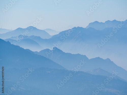 Amazing aerial landscape at the Alps in winter season. Foggy and humidity in the air. Italian alps. Silhouette of the mountains and summits