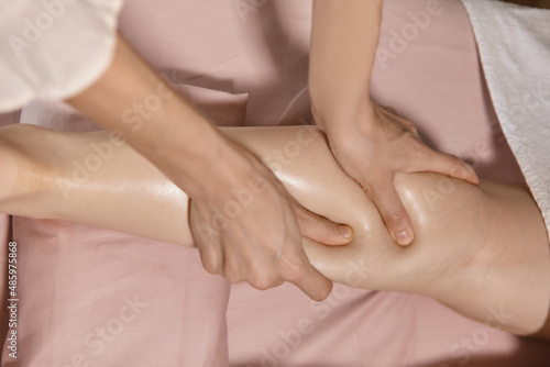 Close up reflexology foot massage. Professional therapist giving calf muscle massage to a woman in spa. Female massage therapist massaging clients legs. Body relaxation and skin care