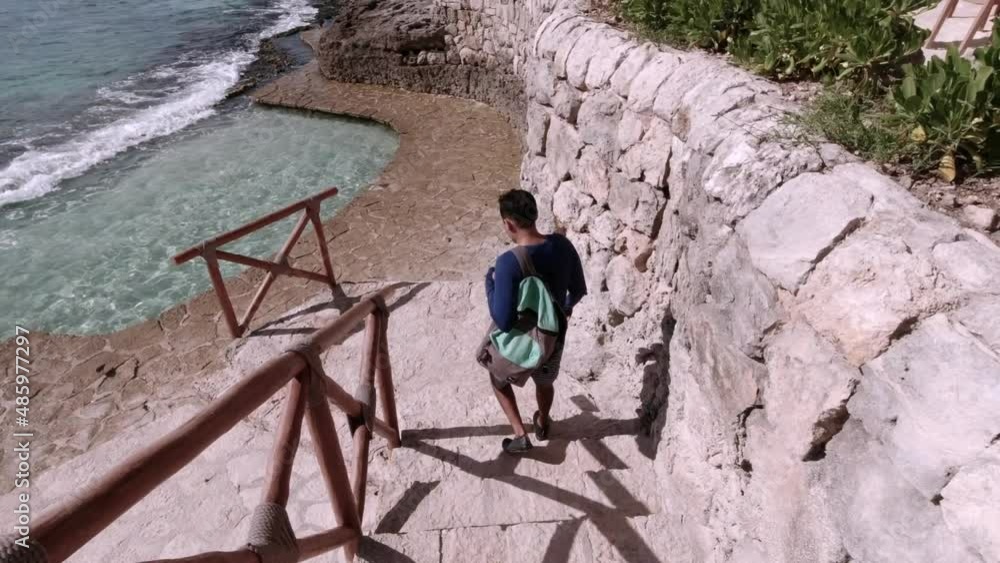 Hispanic Male walking Down Staircase to Natural Water Pool at Xcaret Park in Mexico Hispanic Male walking Down Staircase to Natural Water Pool at Xcaret Park in Mexico