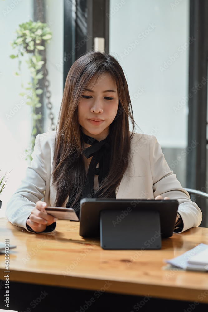 Attractive business woman holding credit card and using digital tablet for banking online. Attractive business woman holding credit card and using digital tablet for banking online.