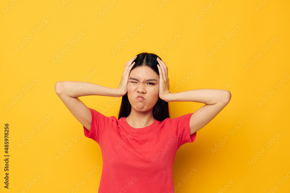 woman with Asian appearance in a red t-shirt posing emotions fun yellow background unaltered woman with Asian appearance in a red t-shirt posing emotions fun yellow background unaltered