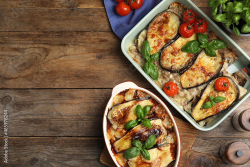 Delicious eggplant lasagna in baking dishes on wooden table, flat lay. Space for text