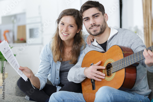 woman holds the music for man playing guitar