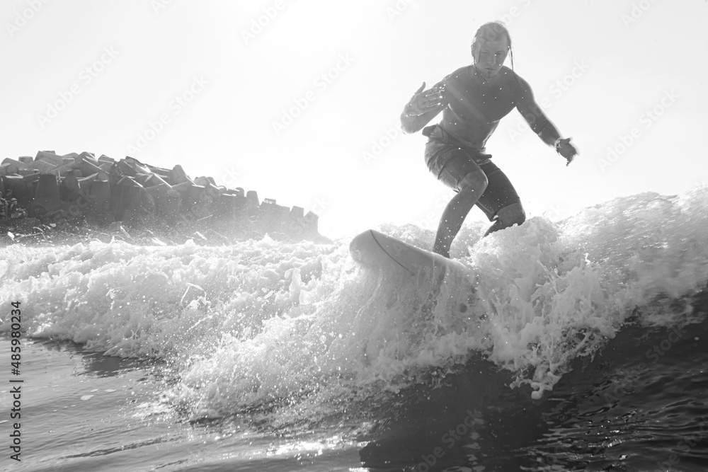 Naklejka premium Young surfer with lean muscular body rides the tropical wave