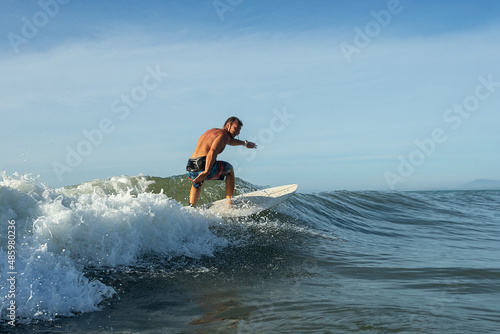 Young surfer with lean muscular body rides the tropical wave © Oleg