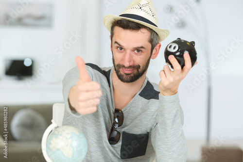 man wearing hat with globe and piggy bank photo