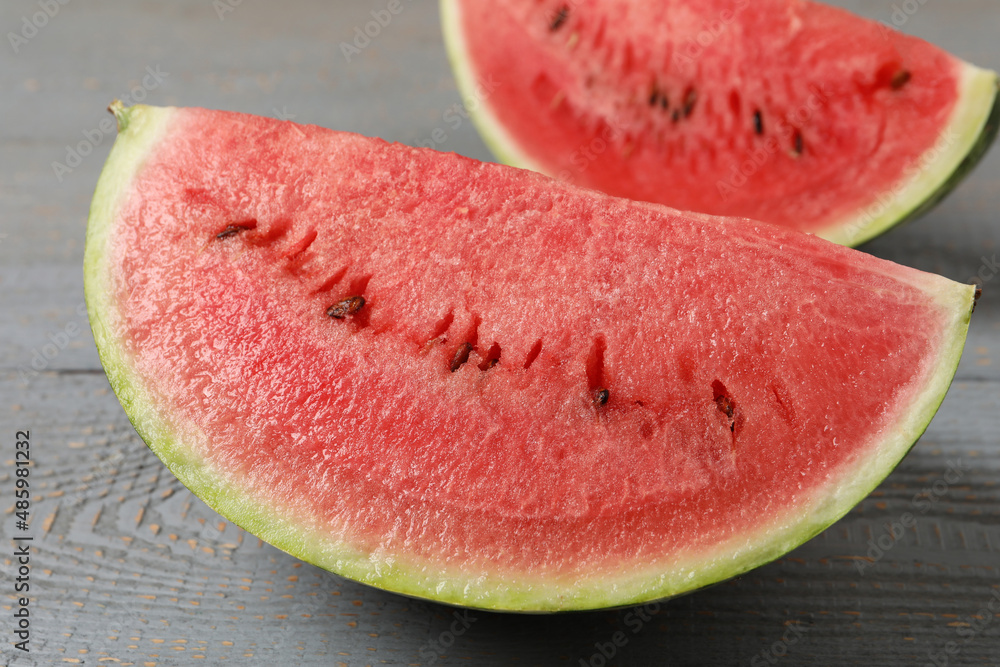 Slices of tasty ripe watermelon on grey wooden table, closeup Slices of tasty ripe watermelon on grey wooden table, closeup