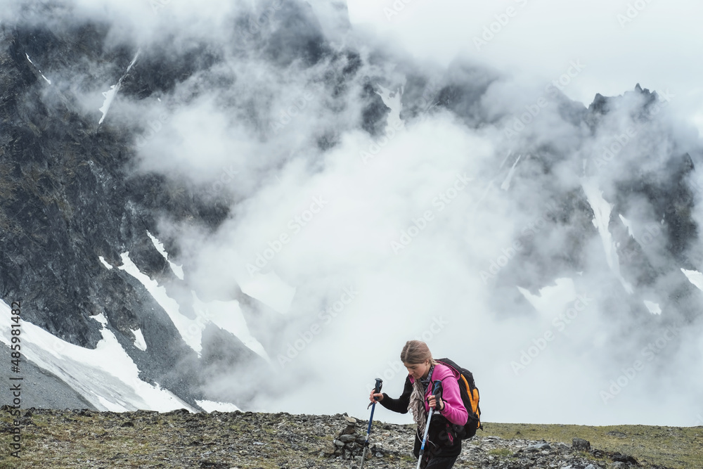 hiker female walking in high mountains. Climbing peak, trekking in Kamchatka