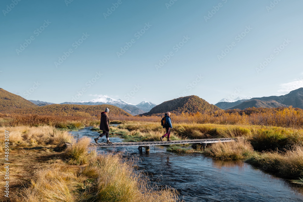 Women friends walking near the river, autumn landscape, first frost on the grass, sunny day, bright colors of nature