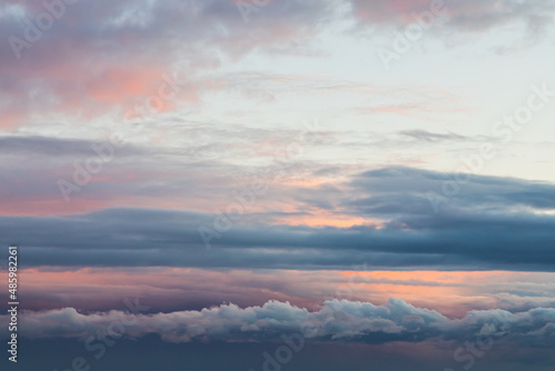 Blue sky background with tiny sunset clouds in summer season. Cloud texture