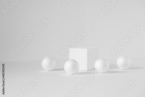 Geometric composition of a cube and balls on an isolated white background. Concept of 3d podium for presentations of packaging and cosmetics. Close-up, copy space.
