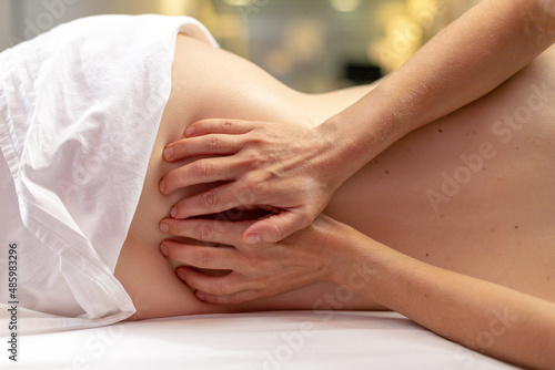 Woman in a spa giving a massage to another woman in the lower back