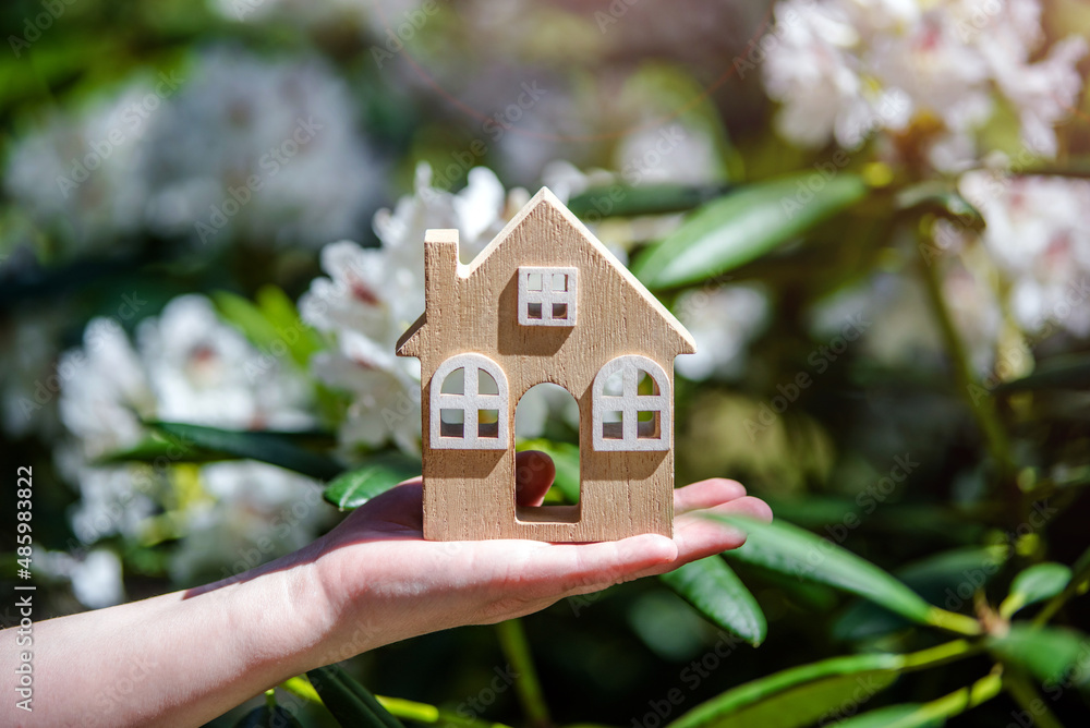 Girl holding a home symbol on a background of white rhododendron
Girl holding a home symbol on a background of white rhododendron
