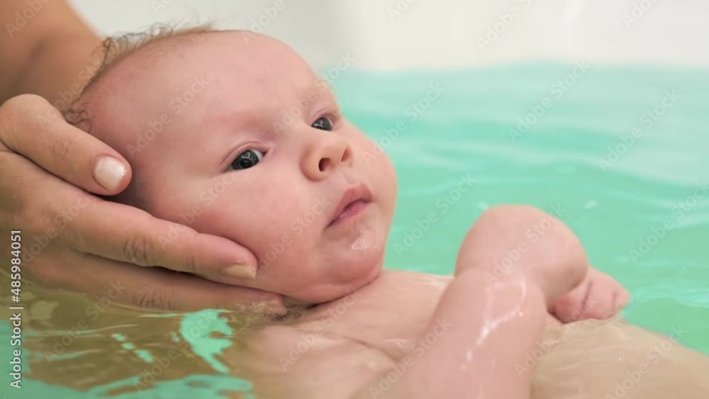Stockvideo Mom teaches a newborn baby to swim and stay on the water. A twomonthold baby is