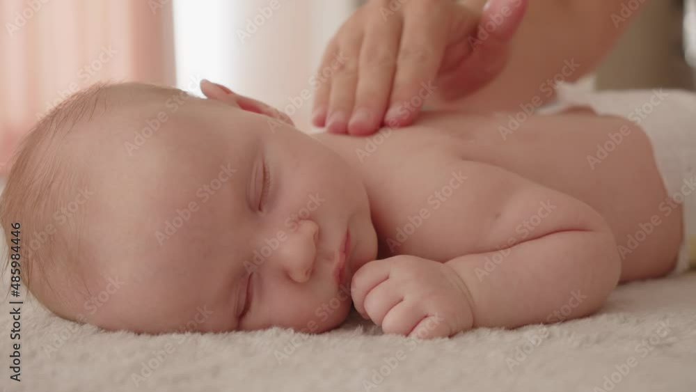 Masseuse pours massage oil on the baby's body and does a massage. Small caucasian newborn lies on his stomach while a masseuse massages his small back and develops muscles. Beauty treatments child . Masseuse pours massage oil on the baby's body and does a massage. Small caucasian newborn lies on his stomach while a masseuse massages his small back and develops muscles. Beauty treatments child .
