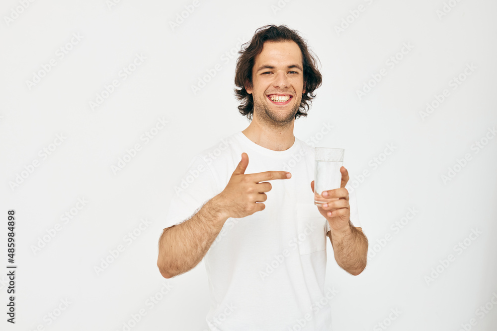 Cheerful man in a white T-shirt glass of water Lifestyle unaltered Cheerful man in a white T-shirt glass of water Lifestyle unaltered