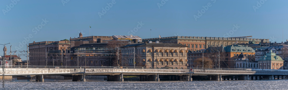 Panorama view, a train bridge at the bay Riddarfjärden with ice floes background with government houses and the royal castle a sunny winter day in Stockholm
